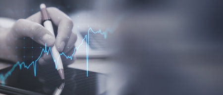 Close up of hand using digital pad with glowing upward business chart on blurry wide perspective...