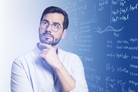 Portrait of attractive young european man in glass with mathematical formulas on blue background. Teacher, math, education and research conceptの写真素材