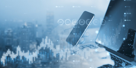 Close up of man hand using laptop and mobile phone with creative candlestick forex chart or graph on...