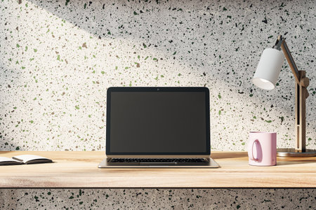 Front view on blank dark modern laptop monitor with place for web design, website or landing page on wooden work table with pink coffee mug and sunlit concrete wall background. 3D rendering, mock upの写真素材