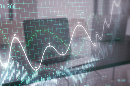 Close up of laptop at workplace with glowing candlestick forex chart on blurry backdrop. Trade, finance and technology concept. double exposureの写真素材