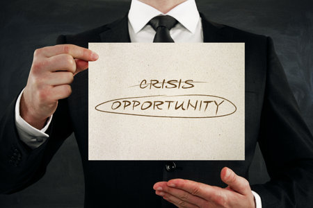 Close up of businessman hands holding paper with creative crisis and opportunity writing on dark wall background. Overcoming difficulties conceptの写真素材
