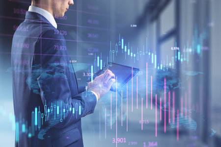 Headless busiessman using tablet with glowing candlestick forex chart on blurry office interior...