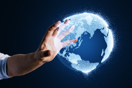Close up of male hand using glowing globe hologram on blurry blue background. Digital earth and metaverse conceptの写真素材