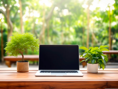 Laptop computer with blank screen on wooden table and green nature background. Generative AIの素材