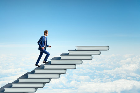 Side view of young man climbing book steps on bright blue sky with clouds background. mock up place. Growth and education conceptの写真素材