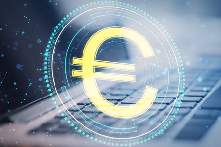 Close up of laptop computer with creative round euro coin and polygonal mesh hologram on blurry background. Digital money and finance concept. double exposureの写真素材