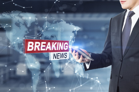 Attractive young European businessman using cellphone with creative hi-tech breaking news and polygonal map hologram on office interior background. Digital communication concept. Double exposure.の写真素材