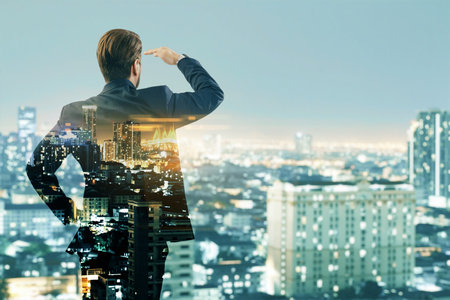 Back view of young business man silhouette looking into the distance on creative night city background. Future, success and career concept. Double exposureの写真素材