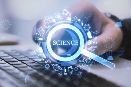 Close up of male hand using laptop keyboard with creative glowing magnifier hologram on blurry background. Science, research and medicine concept. Double exposureの写真素材