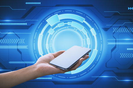 Close up of female hand holding cellphone on creative round blue hi-tech background. Technology and...