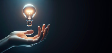 Close up of human hand holding glowing light bulbon dark background with empty space. Generative AIの素材