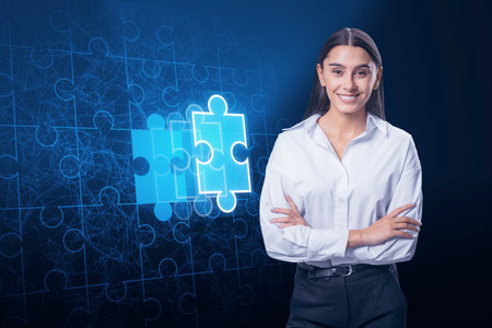 Attractive happy young European businesswoman with folded arms and abstract glowing jigsaw puzzle on blue background. Digital solution, collaboration, partners, merge, matching conceptの写真素材