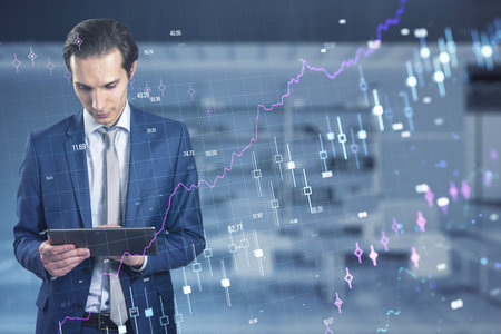 Attractive young European businessman using digital pad with glowing forex chart and grid hologram...
