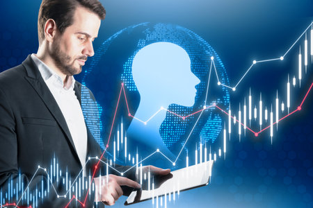 Attractive young businessman using tablet with abstract glowing forex chart and human head outline on blue background. AI, big data, trade and human mind conceptの写真素材