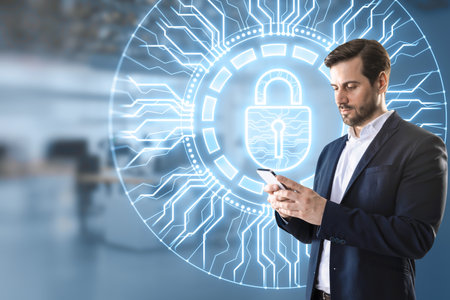 Young businessman using mobile phone with creative glowing round padlock hologram with circuit on blurry office interior background. Secure, web protection and antivirus conceptの写真素材