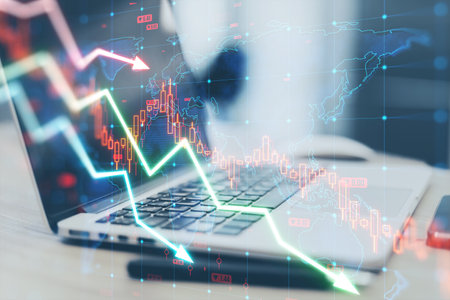 Close up of laptop computer and pen on desk with falling forex chart arrows on blurry background....