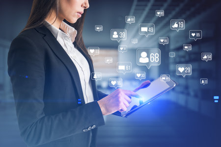 Businesswoman hands using smartphone with creative social media icons hologram on blurry office interior background. Community, likes, shares and communication conceptの写真素材