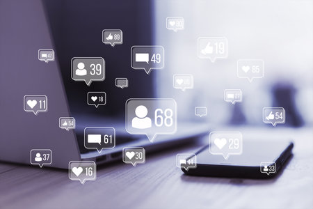 Close up of laptop on desk with tablet and creative social media icons hologram on blurry...