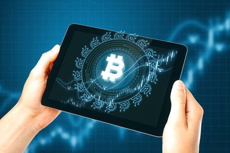 Close up of businessman hands holding tablet with creative glowing bitcoin on dark blue background with candlestick. Cryptocurrency, digital money and economic network conceptの写真素材