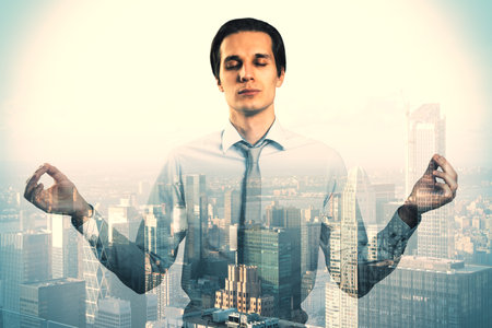Meditating young businessman silhouette on blurry bright city background. Success, future and tomorrow concept. Double exposureの写真素材