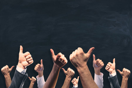 Various male and female hands showing thumbs up on chalkboard wall background with mock up placeの写真素材