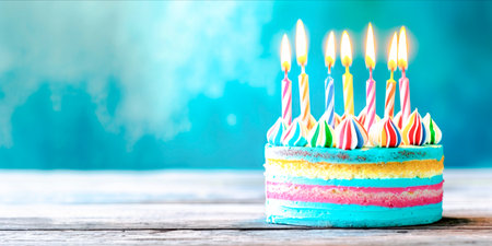 Colorful layered birthday cake with lit candles on turquoise background. Party themeの素材