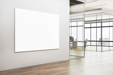 A modern office interior with a large blank poster on a wall, glass partitions, and city view through the windows, concept of advertising. 3D Renderingの写真素材