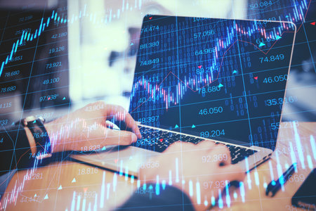 Close up of businessman hands using laptop keyboard with creative candlestick forex chart with index...