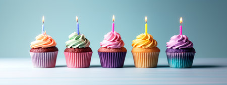 Colorful cupcakes with lit candles on a light blue background, celebrating a concept of birthdays or parties. Generative AIの素材