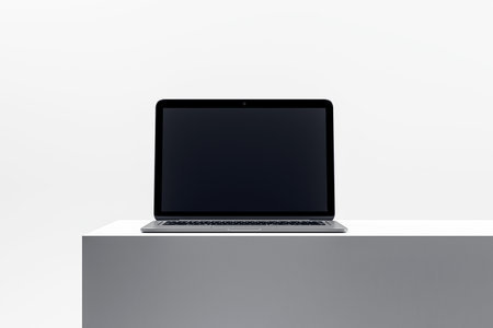 Sleek laptop on minimalist pedestal, displaying a blank screen, ideal for technology and device...