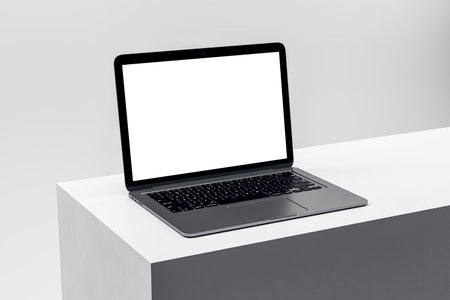 Elegant laptop on a clean white pedestal, featuring a blank screen for advertising and professional...