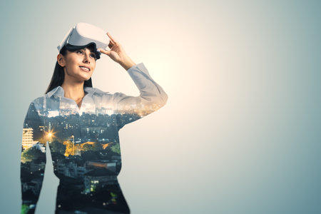 Attractive young European businesswoman with VR glasses standing on blurry city background with mock up place. Metaverse and virtual reality concept. Double exposureの写真素材