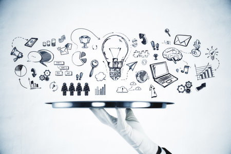 A waiter's hand holding a silver tray with various hand-drawn business and creative concept doodles on a white backgroundの写真素材