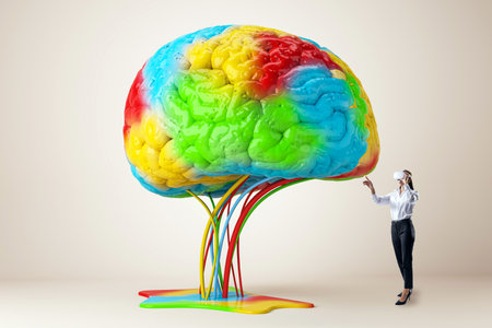 A person interacting with a large, colorful brain model on a neutral background, concept of creativity and ideasの写真素材
