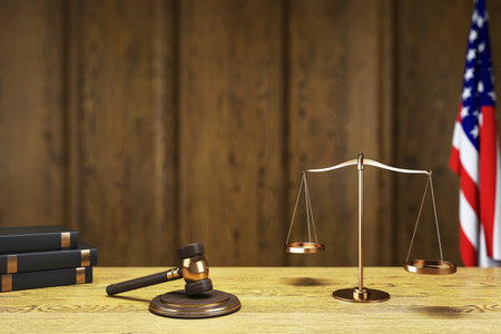 Gavel, scales of justice, and law books on a wooden table with a blurred wooden background and an American flag. Concept of law and justice. 3D Rendering.の写真素材