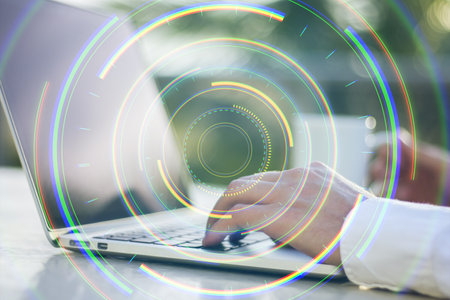 Hands typing on a laptop, overlayed with futuristic holographic circles. Blurred outdoor background. Concept of technology and innovationの写真素材