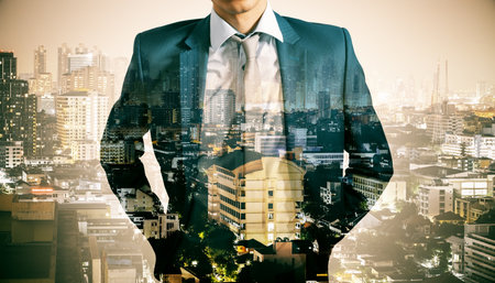 Headless young businessman standing on abstract night city background. Future, success and growth concept. Double exposure.の写真素材