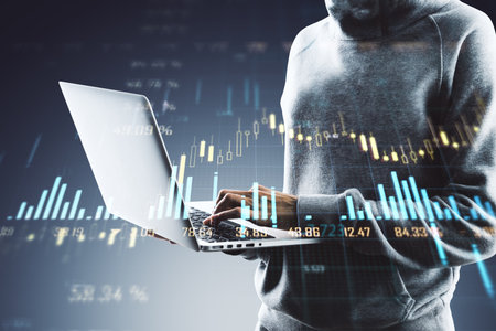 Person using a laptop with financial graphs and charts overlay on a dark background. Concept of technology in finance and tradingの写真素材