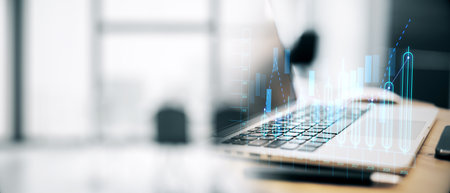 Financial graph overlaying a laptop on a wooden desk in an office. Concept of technology, business analysis, and researchの写真素材