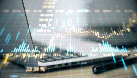 Double exposure of financial charts over a laptop and pen on a wooden desk surface, illustrating the concept of market analysis and tradingの写真素材