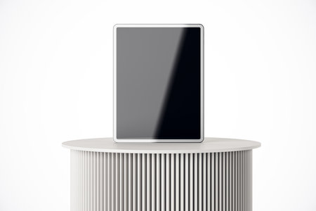 Modern tablet with a blank, black screen standing on a white cylindrical table with vertical grooves, set against a plain white background. 3D Renderingの写真素材