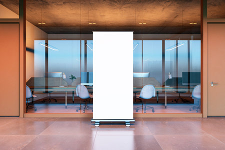 Modern office interior featuring an empty meeting room with glass walls, a roll-up banner in the...
