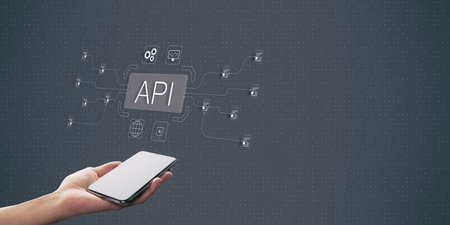 A hand holding a smartphone with API connections illustrated in a modern graphic style on a dark...