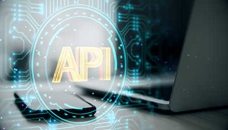 Close up of laptop and phone on desk with creative API hologram on blurry background. Application...