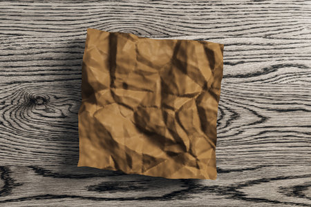 Close up of wrinkled brown piece of paper on wooden desk background. Supplies, stationery, school,...