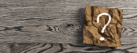 Close up of wrinkled brown piece of paper with question mark on wide wooden desk background with mock up place. Supplies, stationery, school, work and education concept. 3D Renderingの写真素材