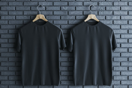 Two empty black t-shirts on gray brick wall background. Mock up place, advertisement concept. 3D Renderingの写真素材