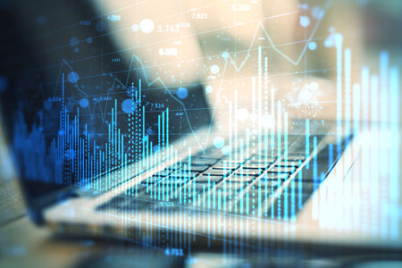 Close up of laptop on desk with glowing blue forex chart on blurry background. Financial growth,...