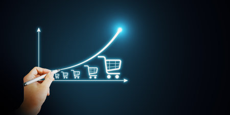 Hand drawing glowing shopping carts on an upward graph, symbolizing ecommerce growth on a dark background. Concept of digital marketingの写真素材